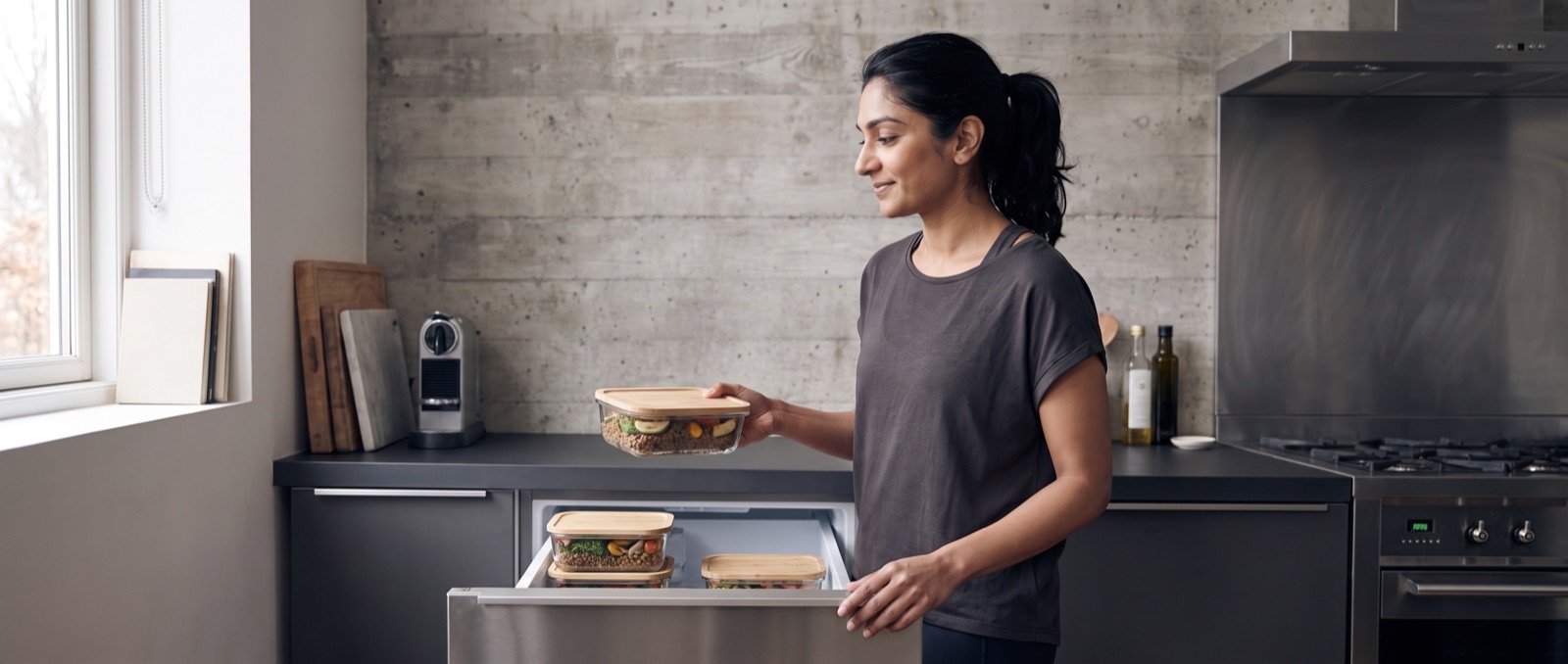 Woman placing a sealed prepared meal into a freezer drawer
